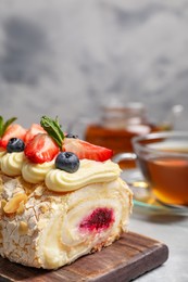 Photo of Tasty meringue roll with jam, cream, strawberry, blueberry and mint on table, closeup
