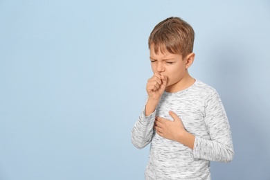 Photo of Little boy coughing on light background
