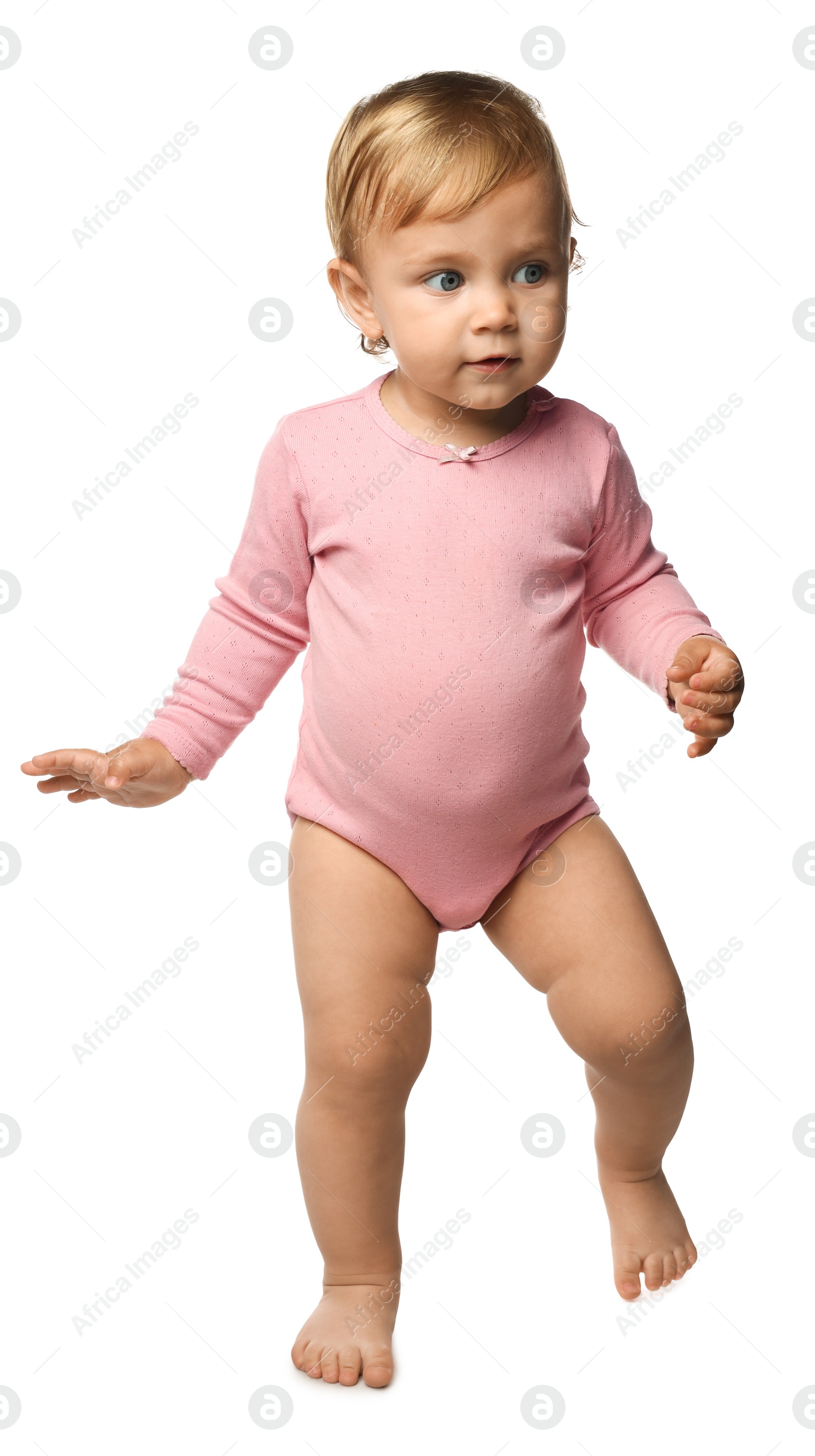 Photo of Cute baby girl in pink bodysuit learning to walk on white background