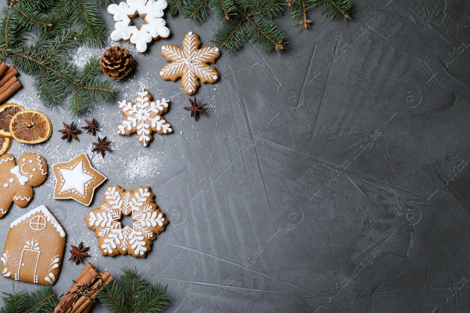 Photo of Decorated Christmas cookies and fir tree branches on grey table, flat lay. Space for text