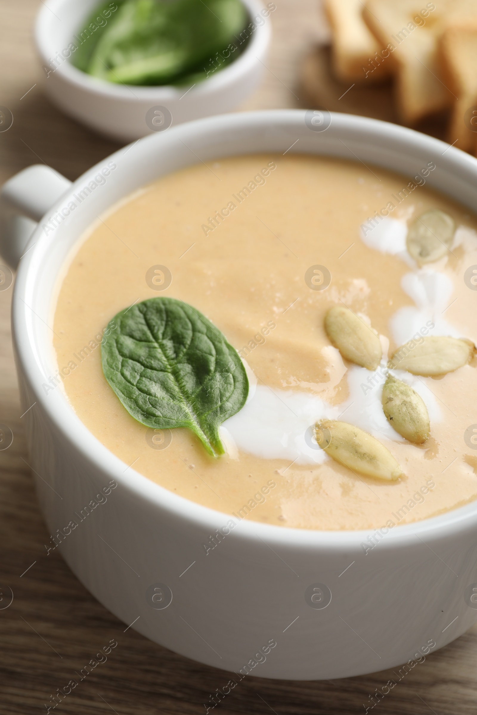 Photo of Healthy cream soup high in vegetable fats on wooden table, closeup