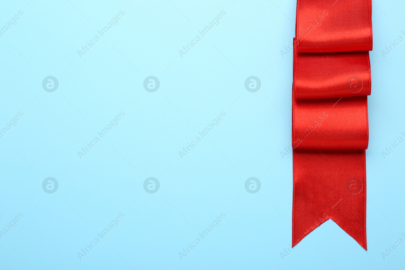 Photo of Beautiful red ribbon on light background, top view. Space for text