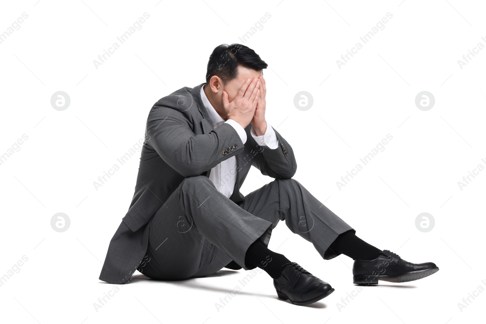 Photo of Tired businessman in suit sitting on white background