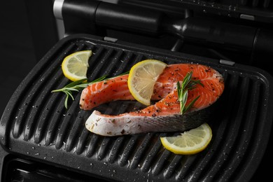 Photo of Cooking salmon. Grill with fresh fish steak, lemon and rosemary