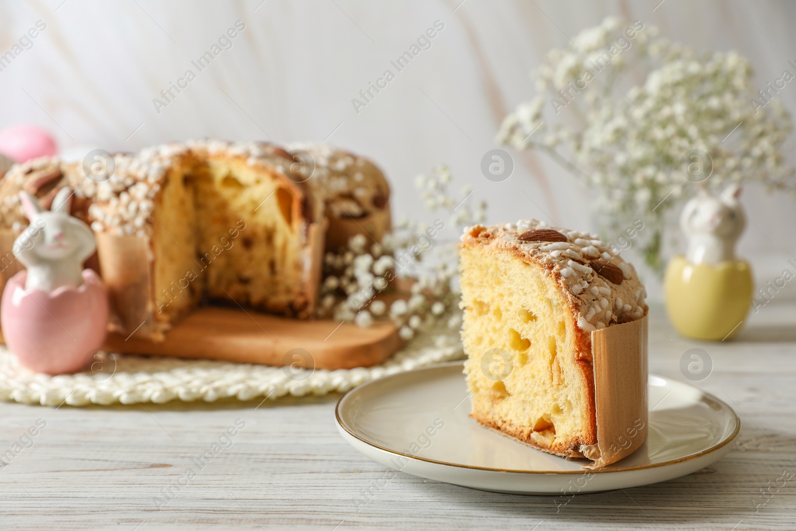 Photo of Delicious Italian Easter dove cake (traditional Colomba di Pasqua) and festive decor on white wooden table