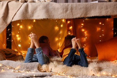 Photo of Kids in decorated play tent at home, back view