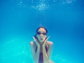 Photo of Beautiful young woman swimming in pool, underwater view