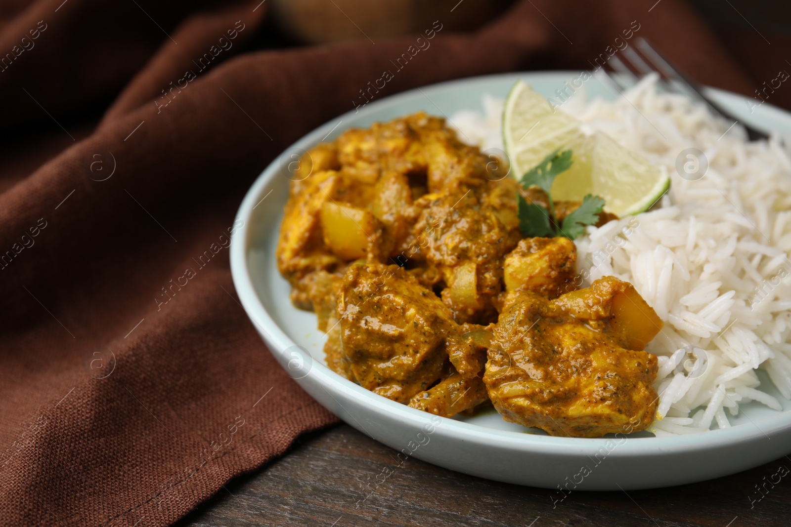 Photo of Delicious chicken curry with rice on wooden table, closeup