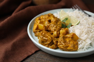 Photo of Delicious chicken curry with rice on wooden table, closeup