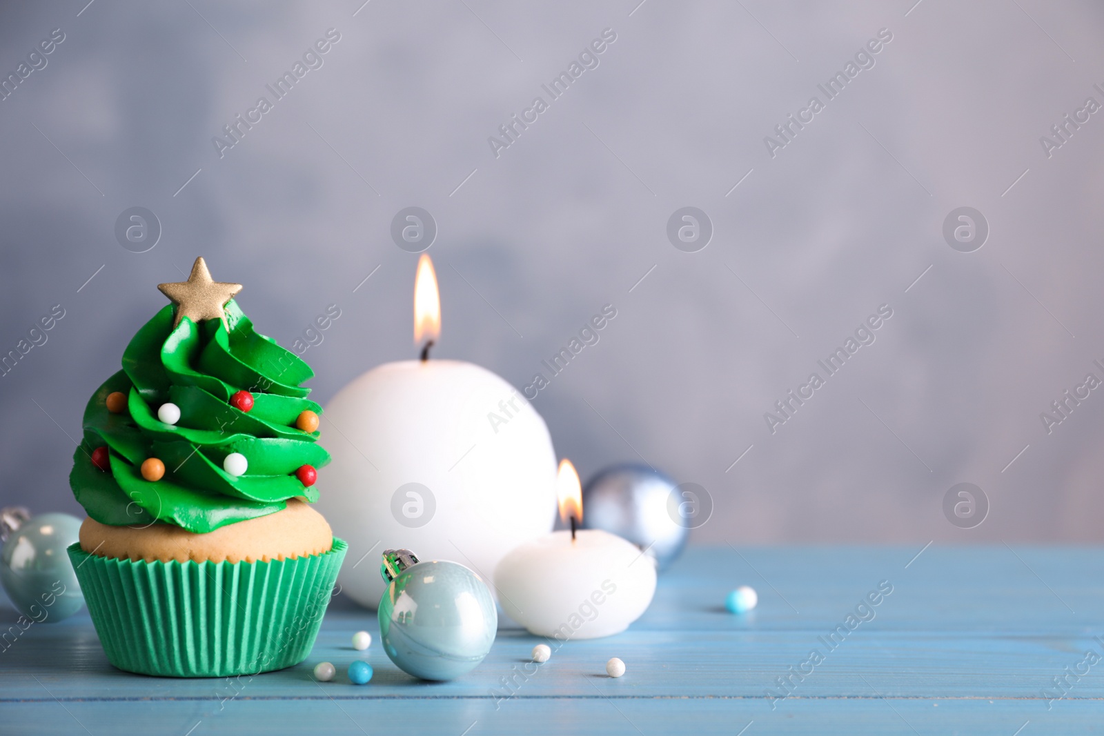 Photo of Christmas tree shaped cupcake and decor on light blue wooden table. Space for text