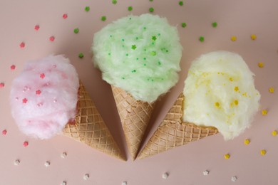 Photo of Sweet cotton candies in waffle cones on beige background, flat lay