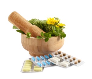 Mortar with fresh green herbs and pills on white background