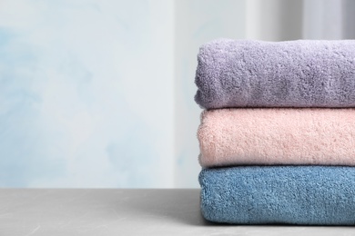 Photo of Stack of soft bath towels on table against blurred background. Space for text