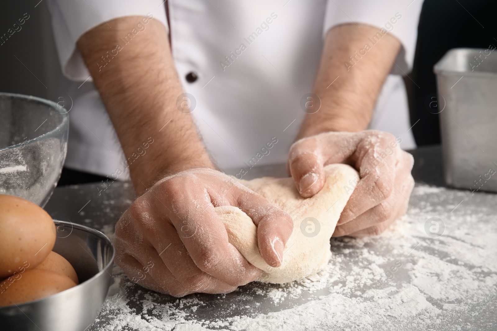 Photo of Man kneading dough for pastry on table