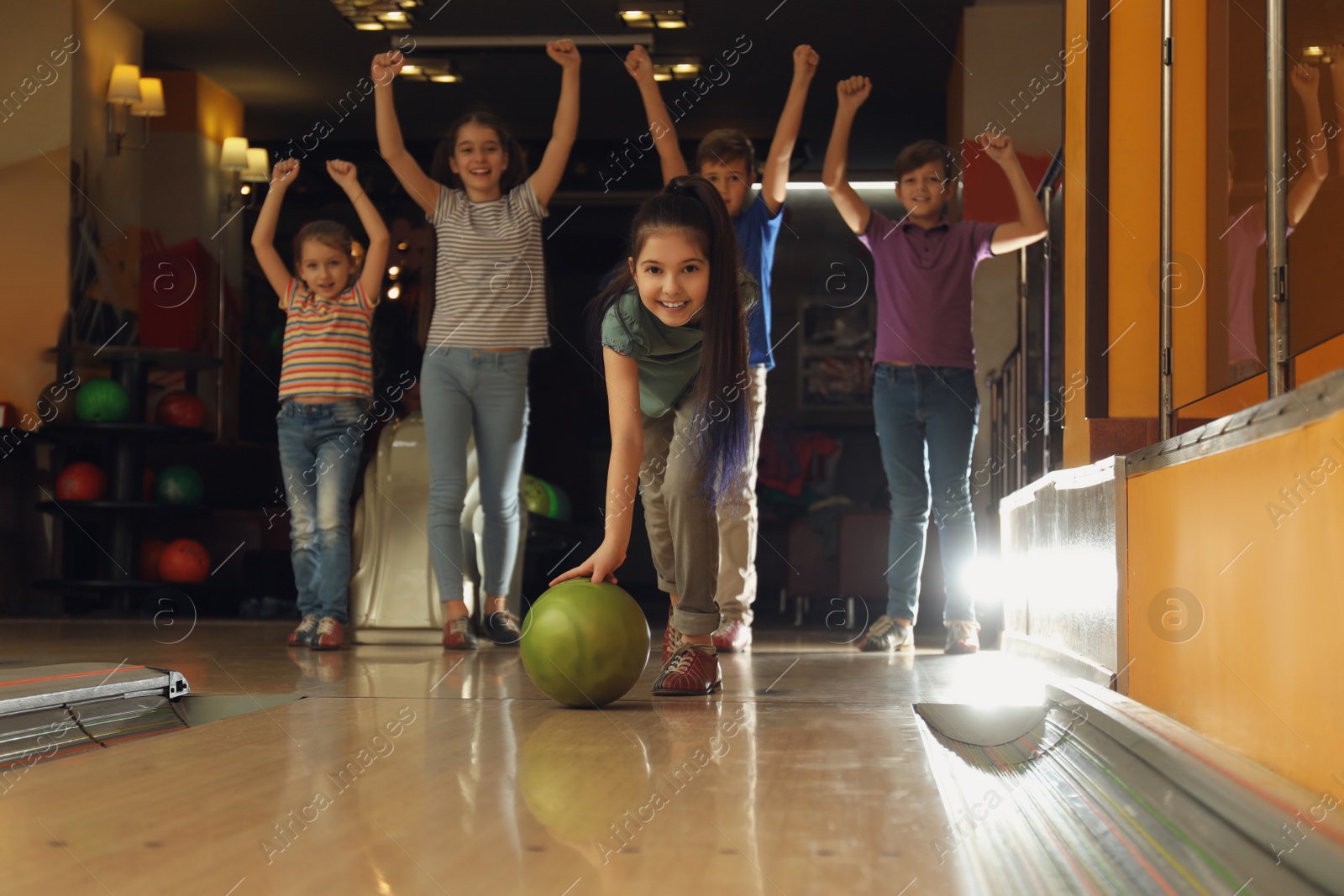 Photo of Girl throwing ball and spending time with friends in bowling club