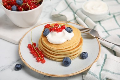 Photo of Tasty pancakes with natural yogurt, blueberries and red currants on marble table