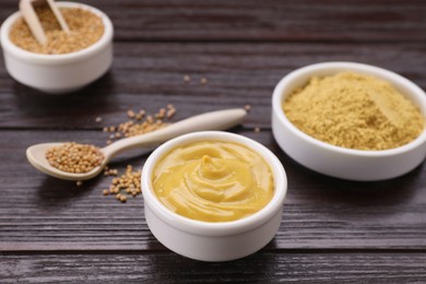 Photo of Delicious mustard and seeds on dark wooden table, closeup