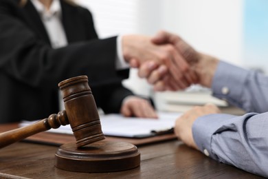 Lawyer shaking hands with client in office, focus on gavel