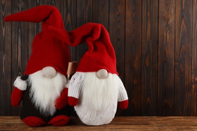 Photo of Two cute Christmas gnomes on wooden table. Space for text