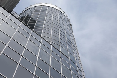 Photo of Modern building with tinted windows against sky, low angle view. Urban architecture