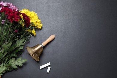 Photo of Golden school bell, bouquet of beautiful chrysanthemum flowers and chalk on blackboard, flat lay. Space for text