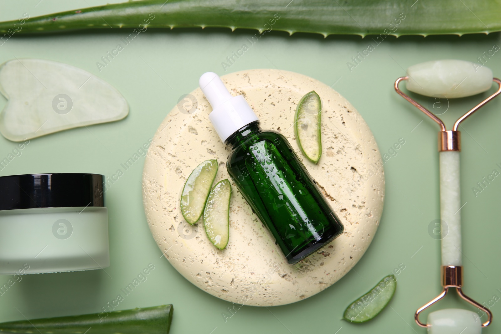 Photo of Flat lay composition with cosmetic products and cut aloe leaves on pale green background