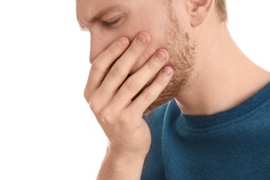 Handsome young man coughing against white background