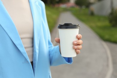 Coffee to go. Woman with paper cup of drink outdoors, closeup