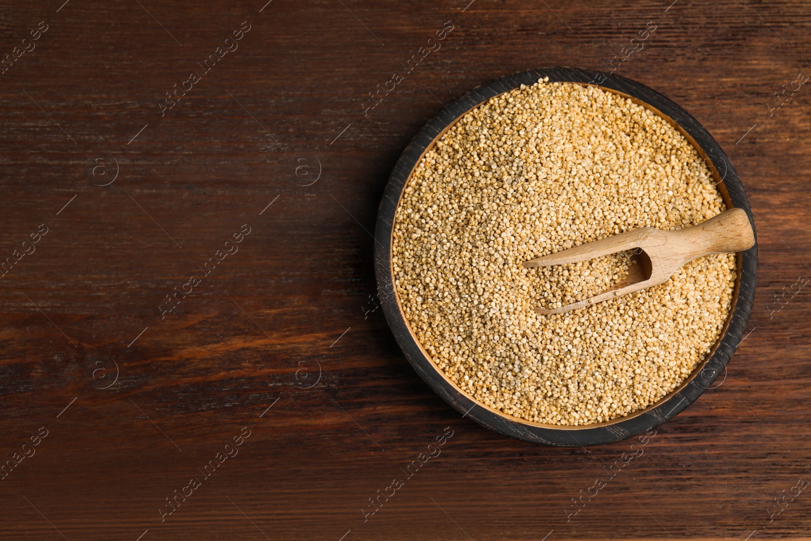 Photo of Plate with white quinoa and scoop on wooden table, top view. Space for text