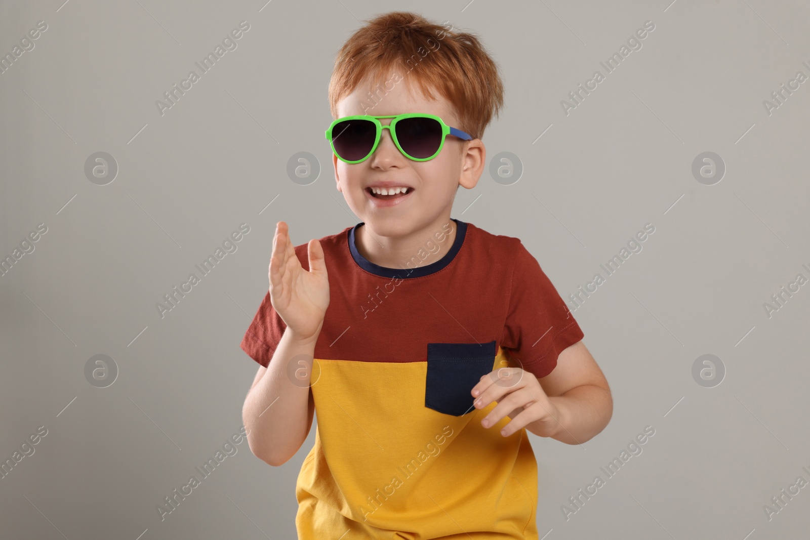 Photo of Cute little boy with sunglasses on light grey background