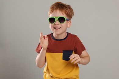 Photo of Cute little boy with sunglasses on light grey background