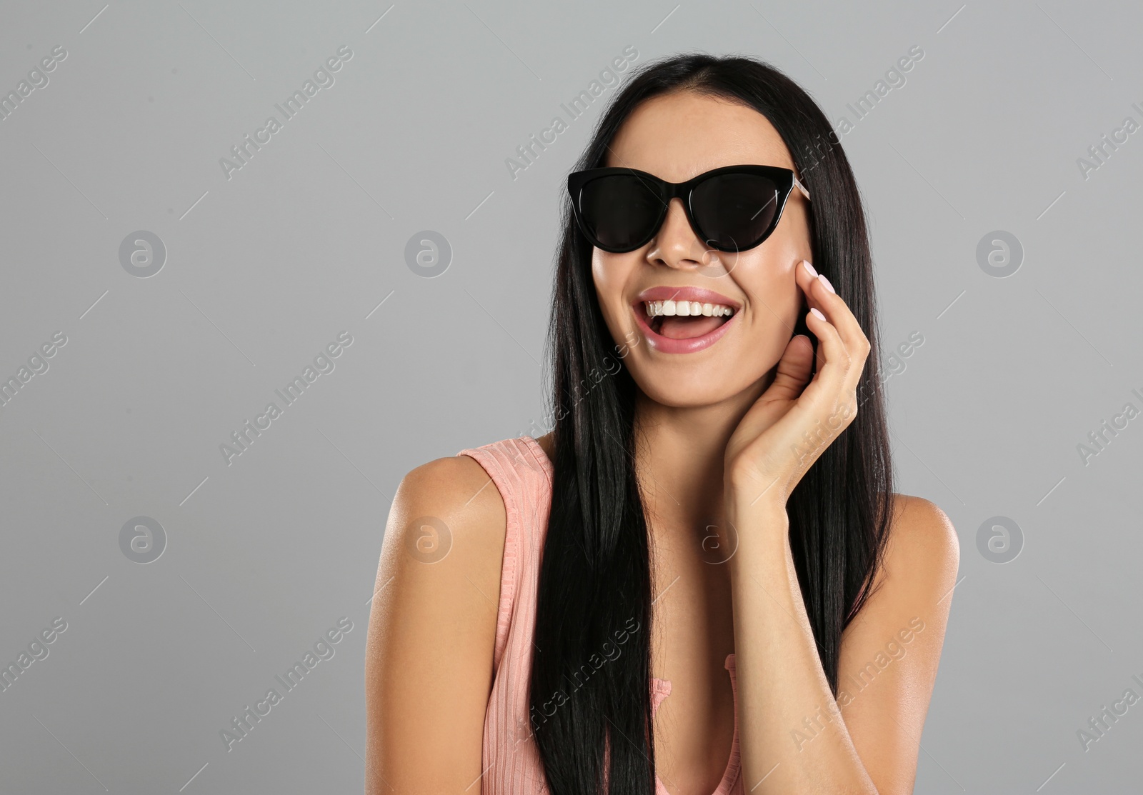 Photo of Beautiful woman wearing sunglasses on grey background. Space for text