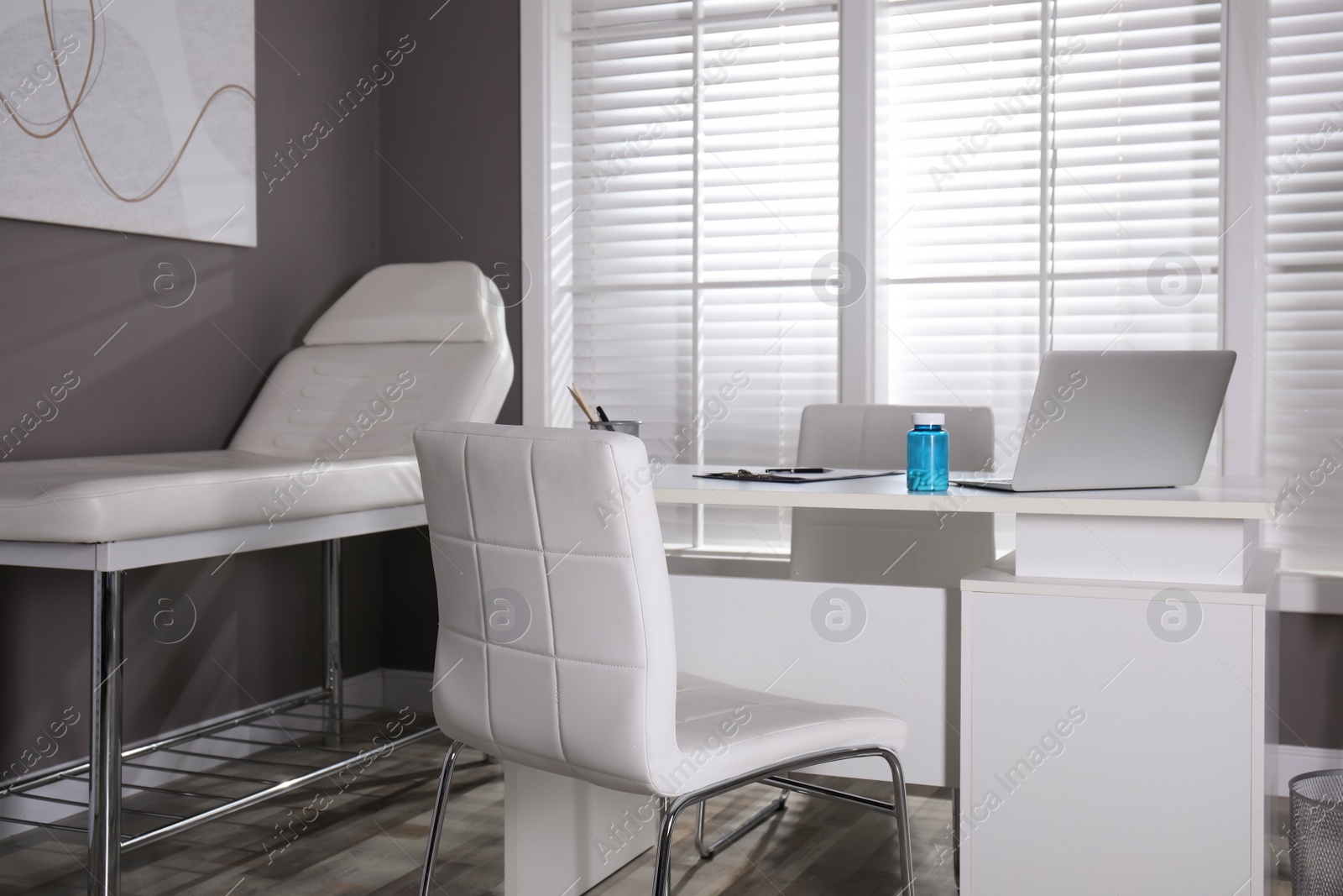 Photo of Modern medical office interior with doctor's workplace and examination table