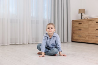 Photo of Cute little boy sitting on warm floor at home. Heating system