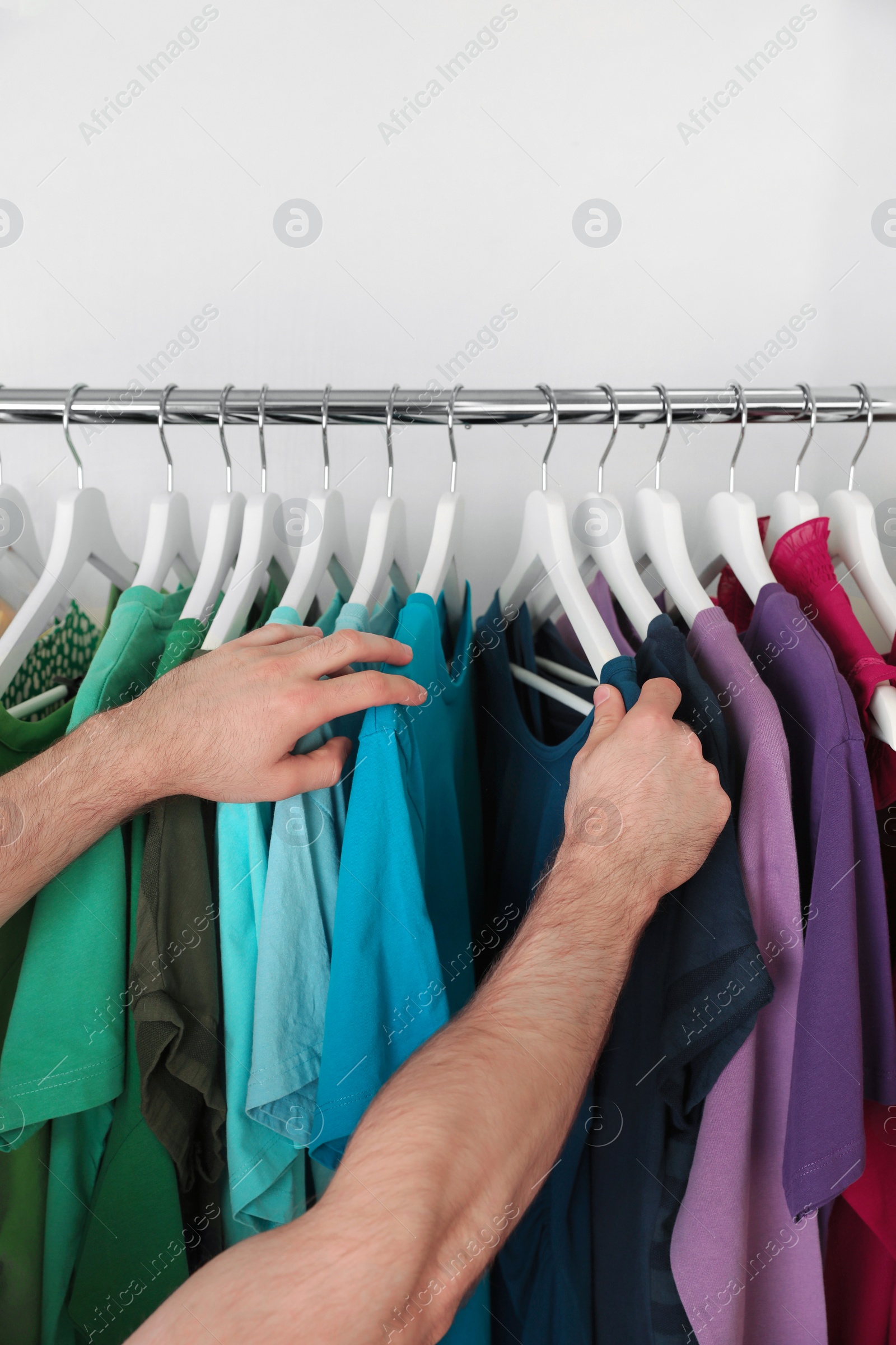 Photo of Man choosing clothes from rack in wardrobe, closeup