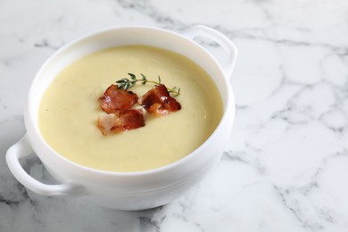 Photo of Tasty potato soup with bacon and rosemary in bowl on white marble table, closeup. Space for text