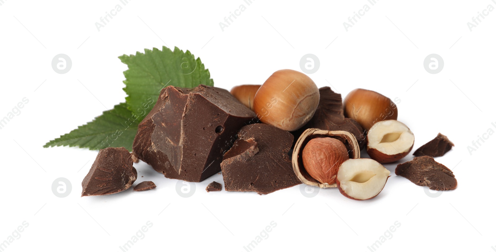 Photo of Delicious chocolate chunks with hazelnuts and green leaves on white background