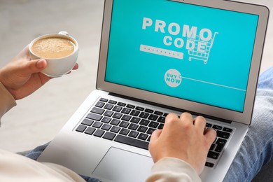 Photo of Man with laptop activating promo code while doing online shopping and holding cup of coffee, closeup