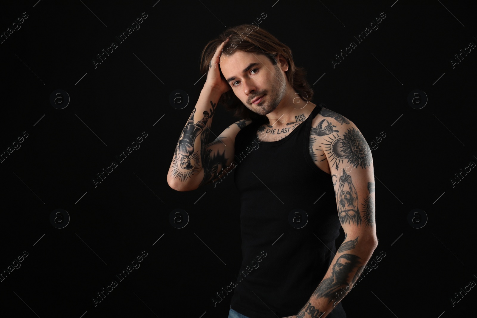 Photo of Young man with tattoos on body against black background