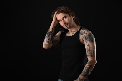 Young man with tattoos on body against black background