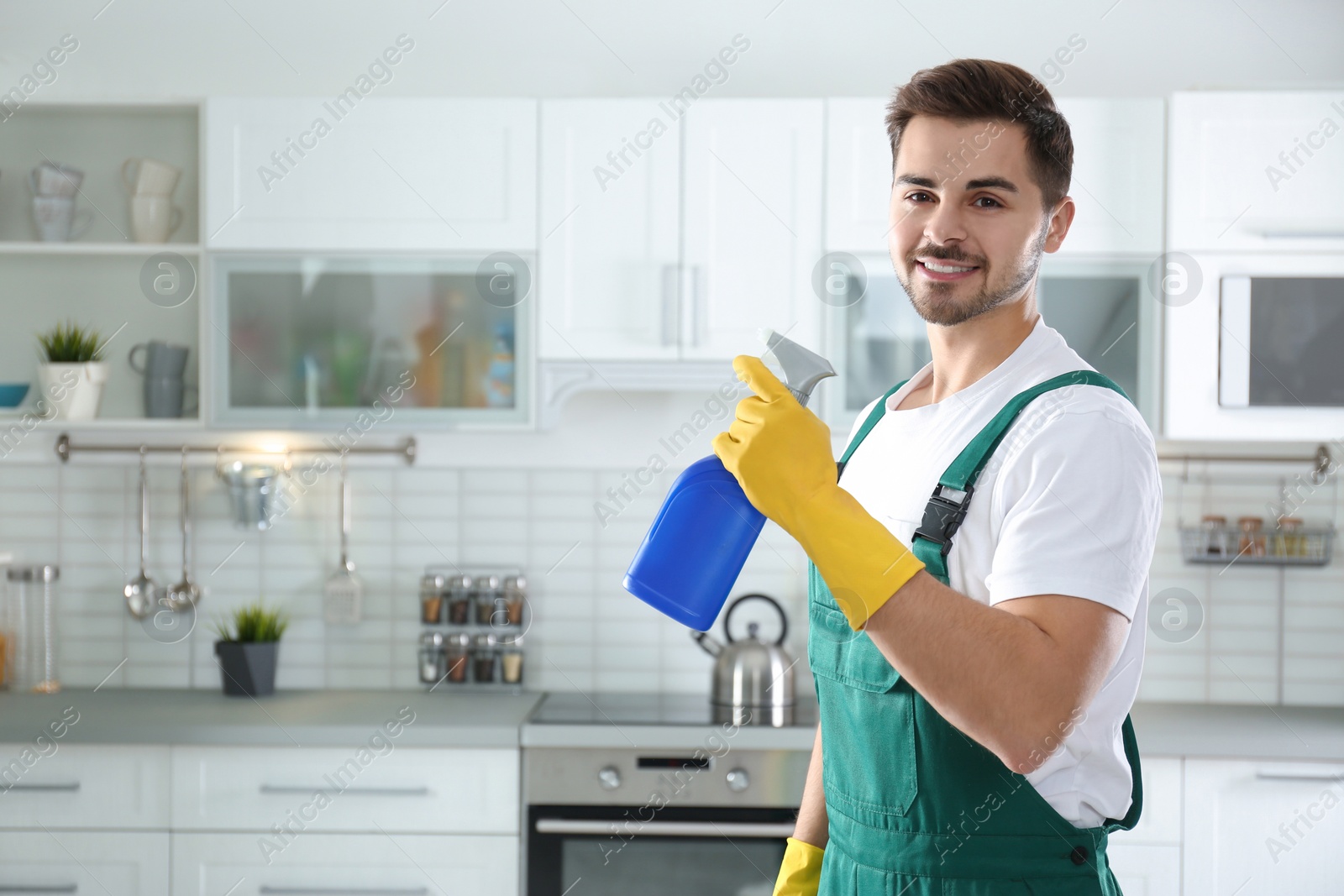 Photo of Portrait of janitor with sprayer in kitchen. Cleaning service