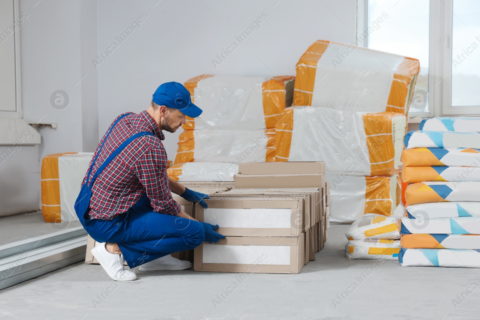Photo of Construction worker with packed new boxes in room prepared for renovation