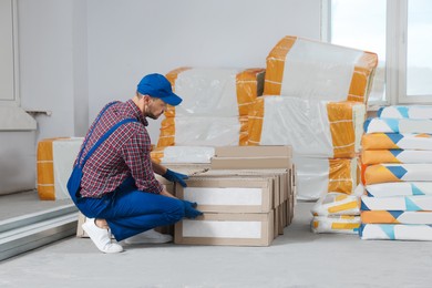 Photo of Construction worker with packed new boxes in room prepared for renovation