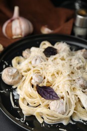 Delicious pasta with mushrooms on black plate, closeup