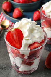 Photo of Delicious strawberries with whipped cream served on grey table, closeup
