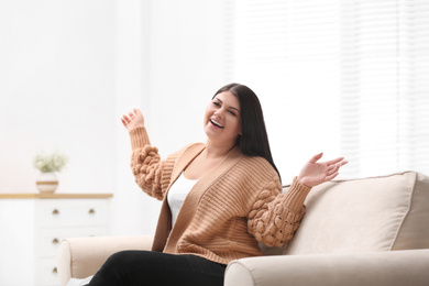 Photo of Emotional overweight woman on sofa in living room. Plus size model