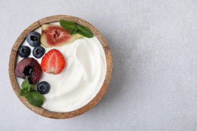 Bowl with yogurt, berries, fruits and mint on light grey table, top view. Space for text