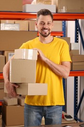 Post office worker with parcels near rack indoors