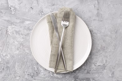 Elegant setting with silver cutlery on grey textured table, top view