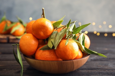 Photo of Bowl with ripe tangerines and blurred Christmas lights on background